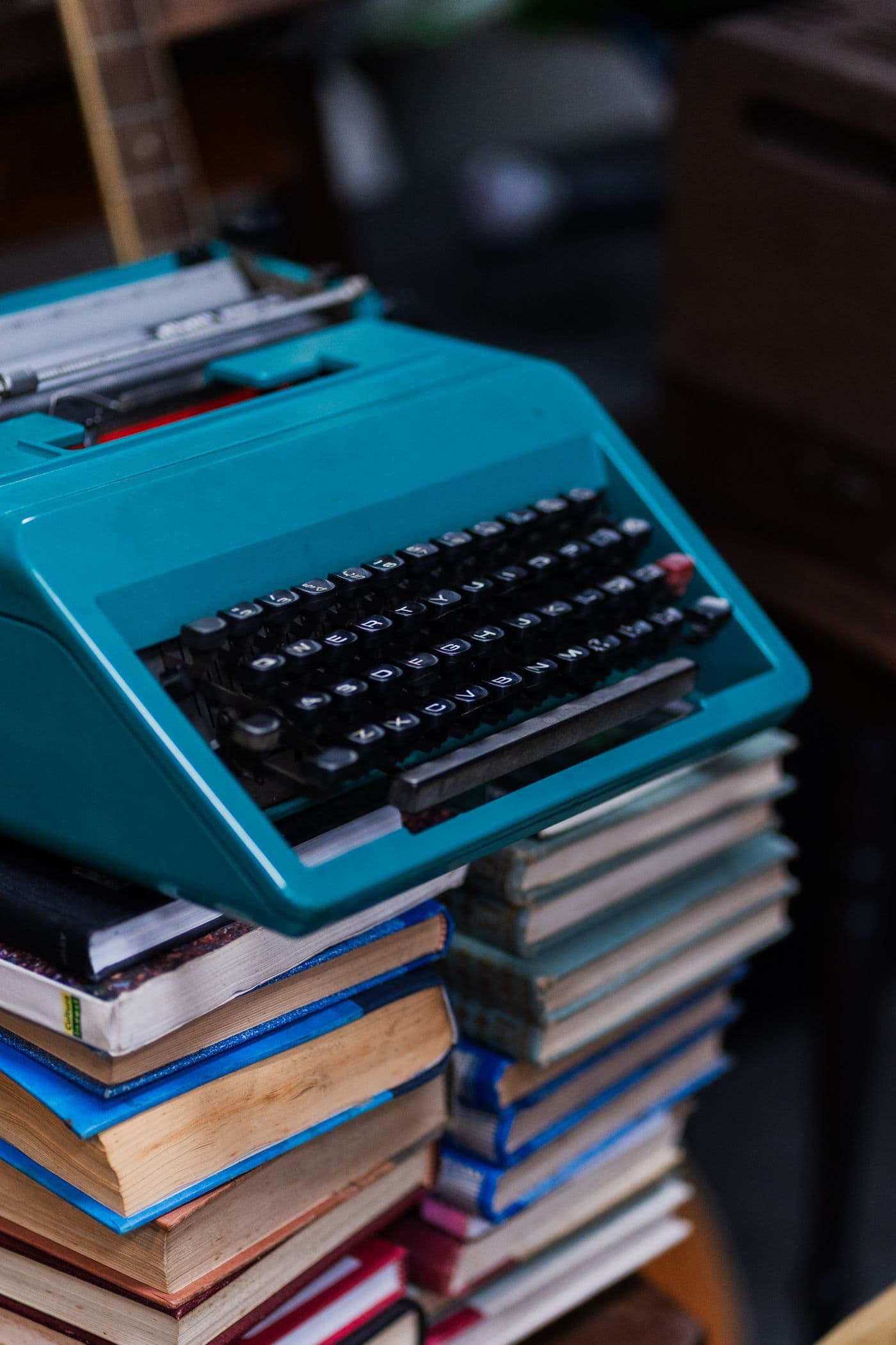 A typewriter resting on a stack of old hardback books